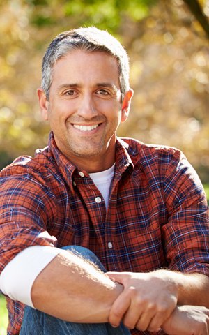 smiling man in plaid shirt who has dental implants