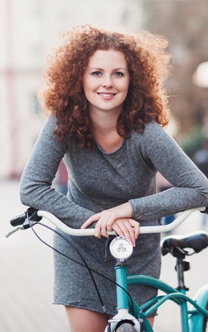 woman with curly red hair on a bike who had a root canal