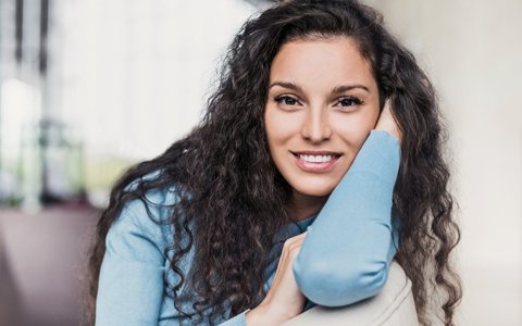 smiling woman with curly hair who used Invisalign