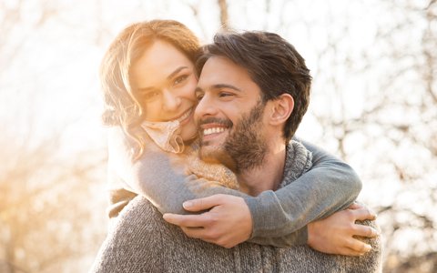 woman hugging a man from behind after getting periodontal disease treatment near Centerport