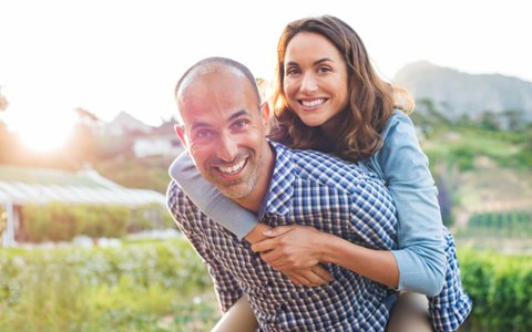 man carrying a woman on his shoulders who had periodontal plastic surgery in Centerport