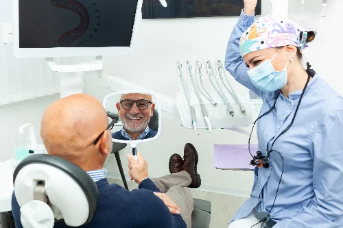 older man smiling in mirror, happy with new impants