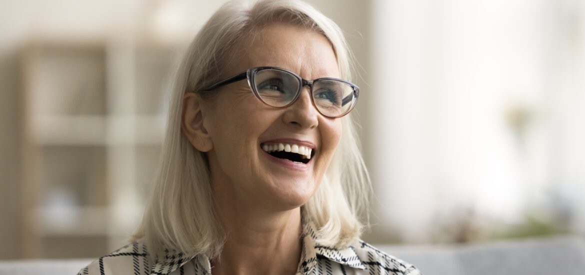 mature woman smiling on a couch, new dental implants