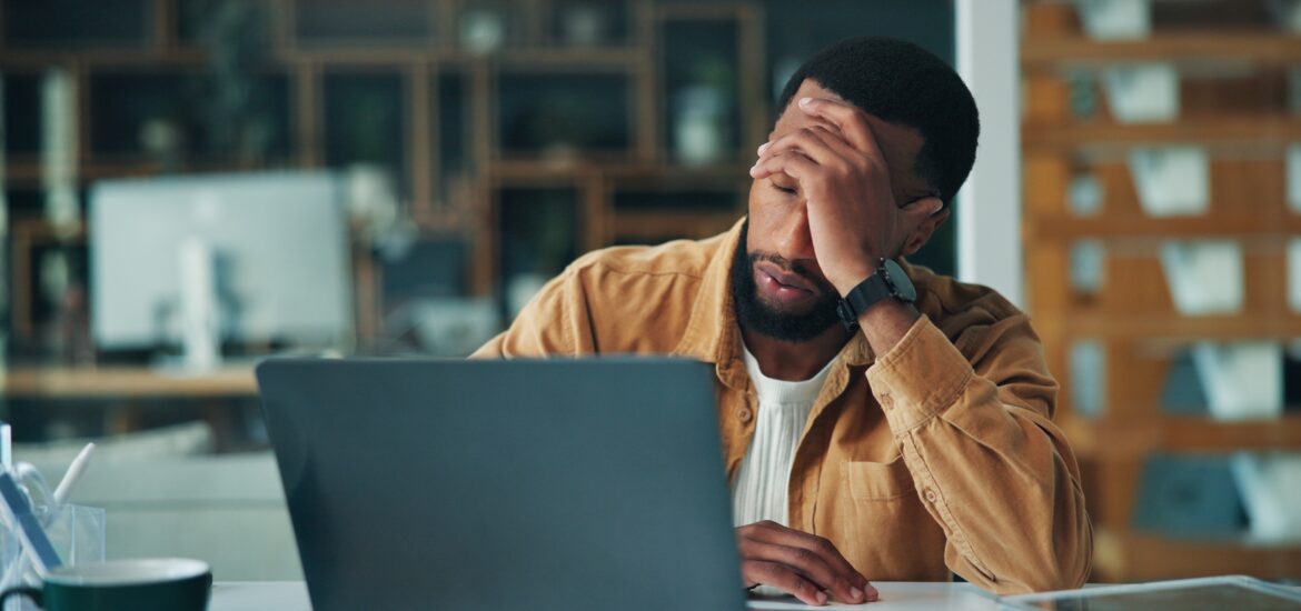 fatigued man sitting at his computer, hand over face