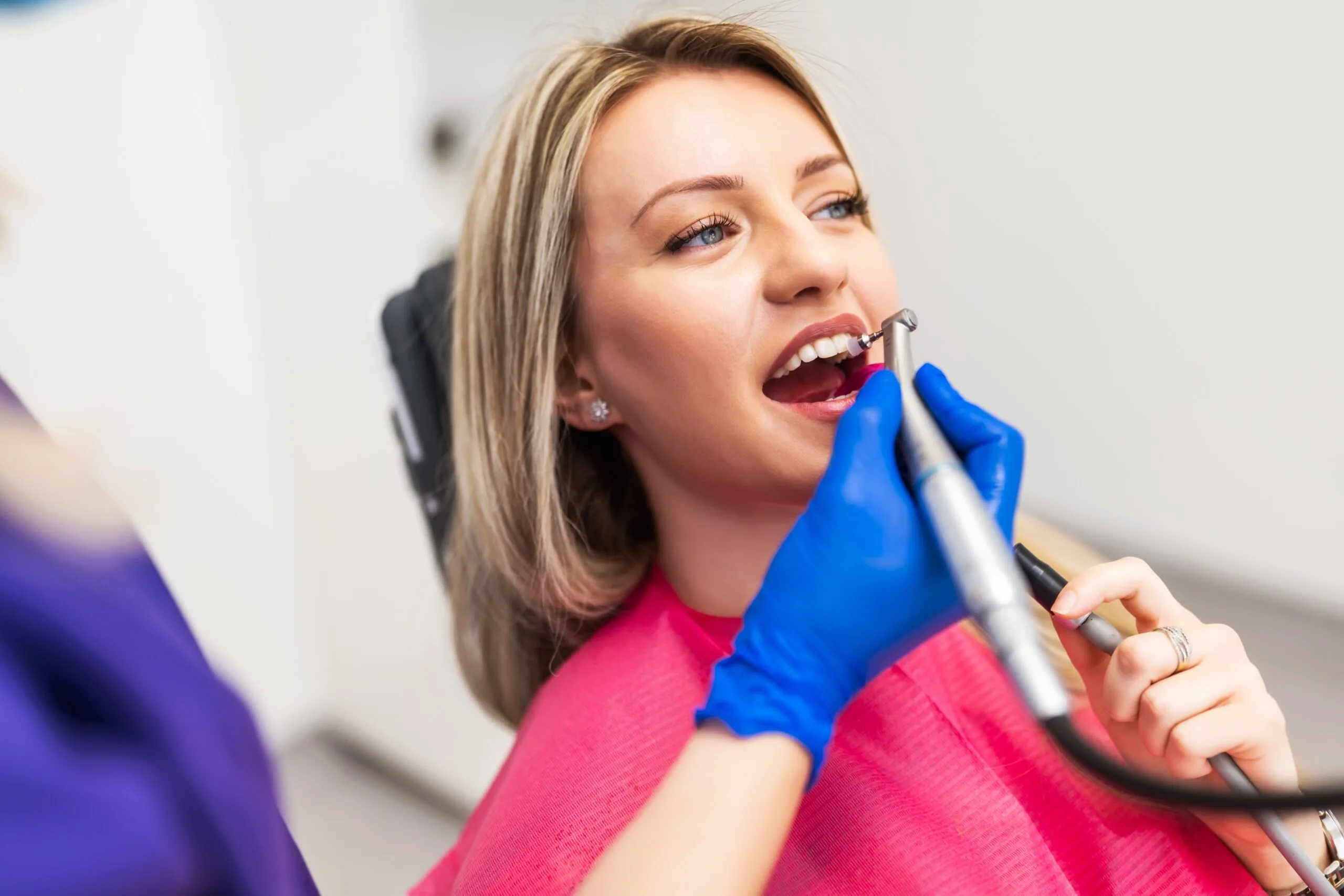 dentist in blue gloves polishing a dental crown